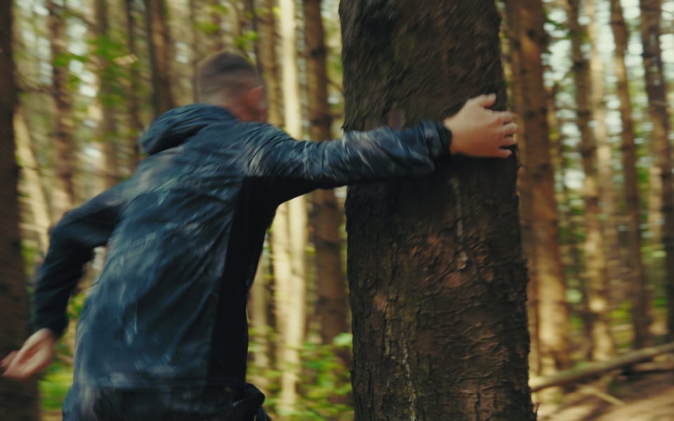 Runner swinging around a tree in a pine forest