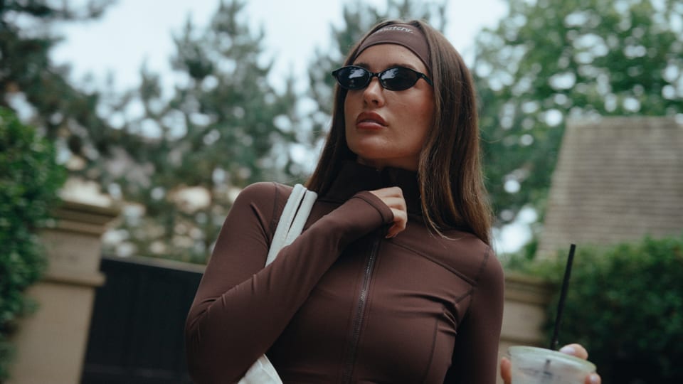 Woman in a brown zip-up activewear jacket and sunglasses