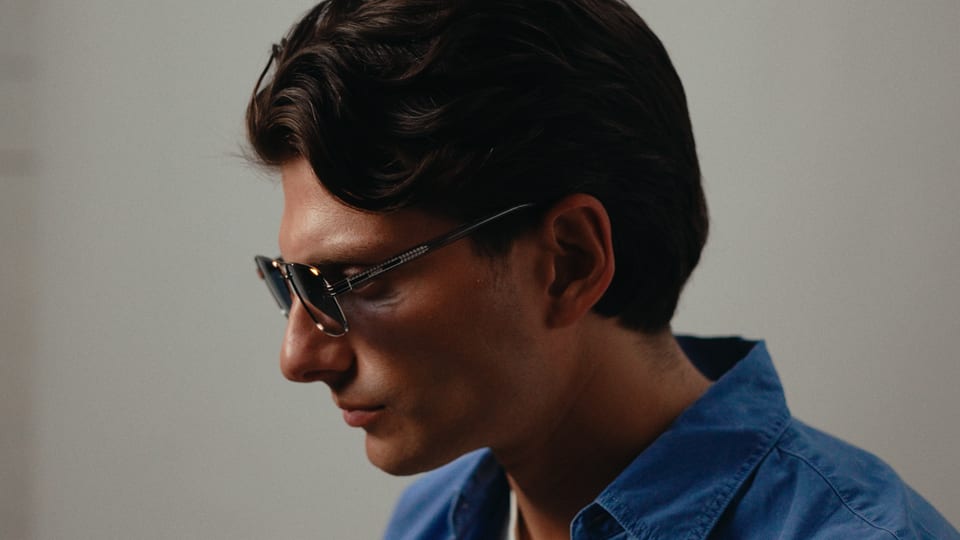 Man in sunglasses and a blue shirt, looking down