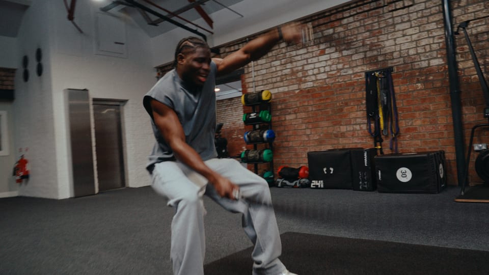 Athlete in a deep lunge in a brick-walled gym