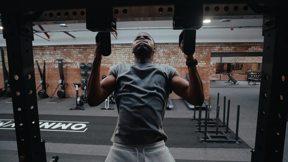 Athlete mid pull-up in an industrial gym
