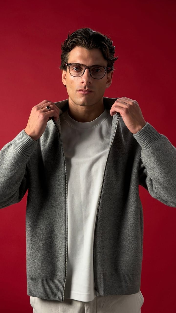 Model in a grey cardigan and glasses against a red backdrop, shot on iPhone