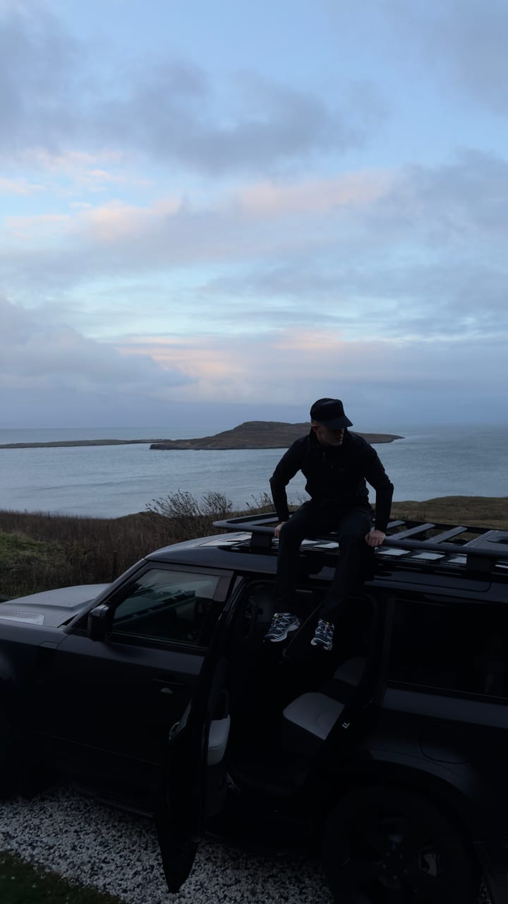 Kyle sitting on a Land Rover Defender above the coast at dusk, shot on iPhone