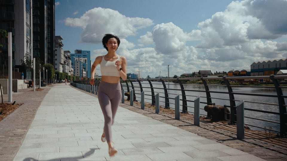 Runner on a riverside path under a cloudy sky